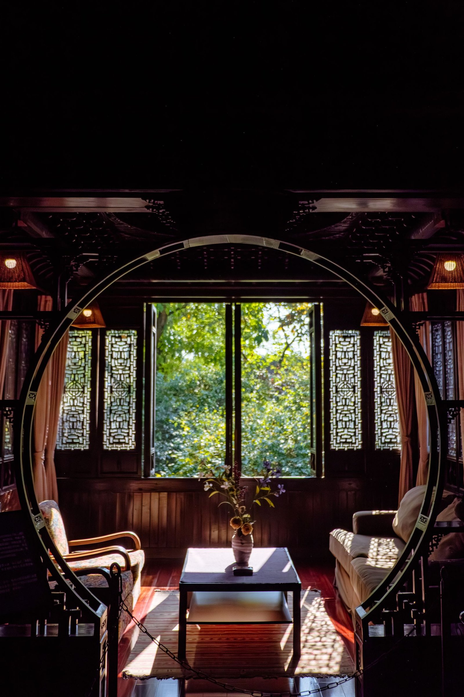 A classic living room interior with wooden decor, circle doorway, and garden view through a window.